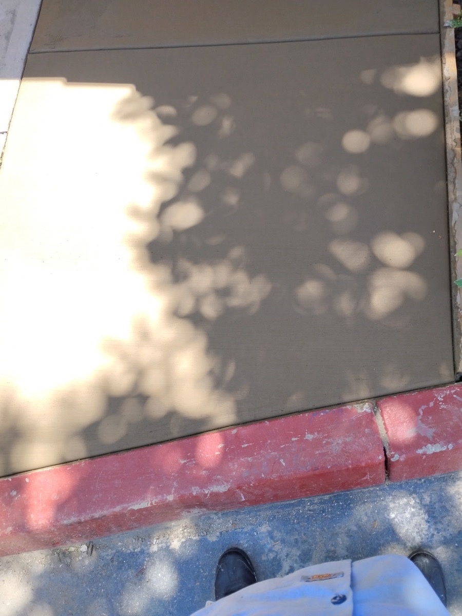 Freshly placed and finished concrete adjoining a painted curb
