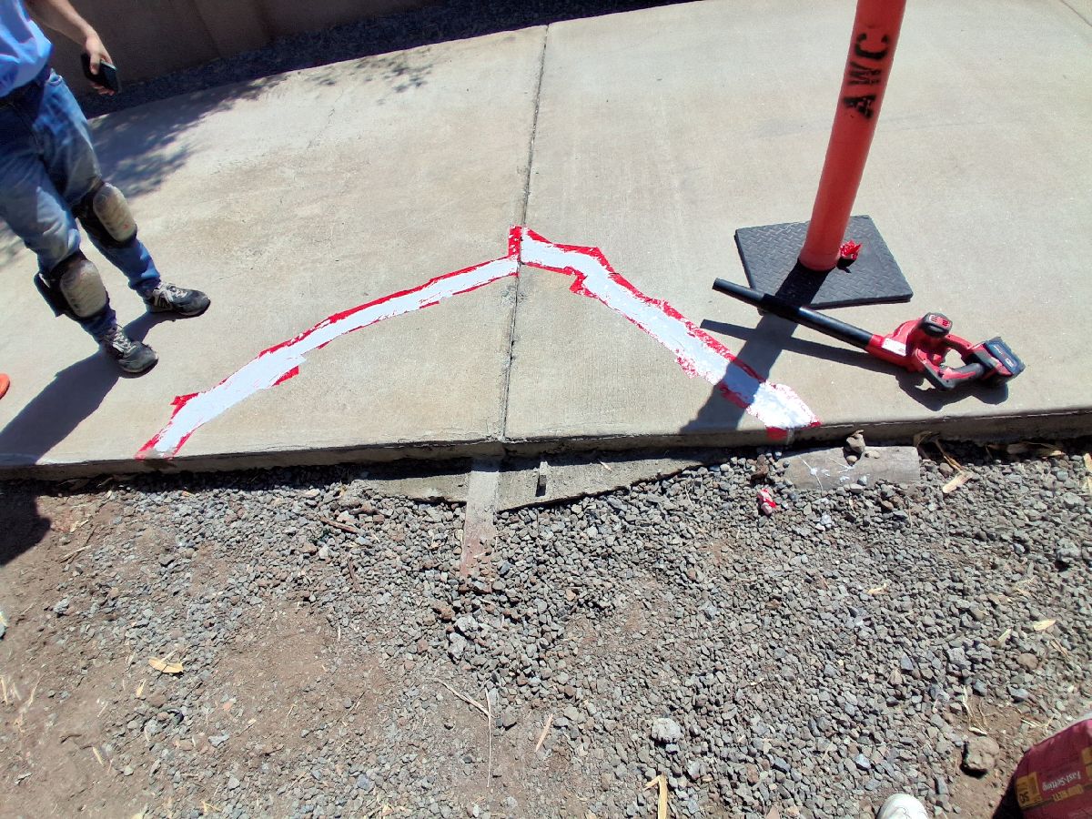 Prepared driveway crack lines with repair materials and tools during localized concrete work